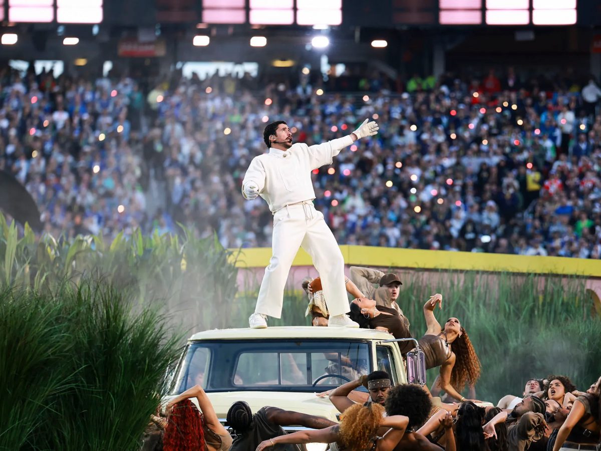 Bad Bunny standing on a truck as backup dancers surround him.