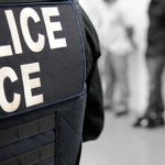 On the back of a uniform is written “Police ICE.”