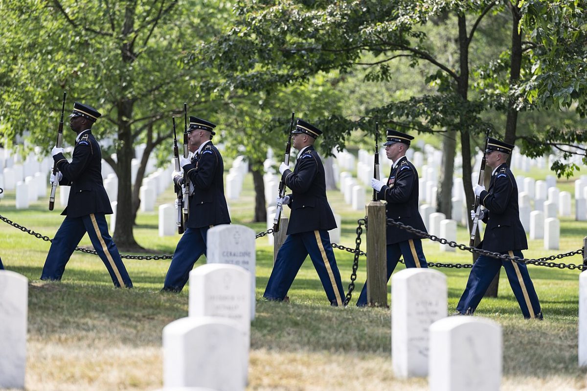 A U.S. Army Honor Guard marching among tombstones of Arlington.