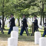 A U.S. Army Honor Guard marching among tombstones of Arlington.
