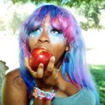 Hemlocke Springs in galaxy wig eating an apple