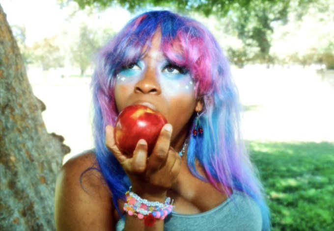 Hemlocke Springs in galaxy wig eating an apple