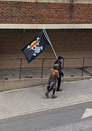 A man holding a “Jolly Rodger’s Straw Hats” flag from the anime One Piece