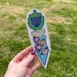 Photo of Imaginary Gardens bookmark for Spring Fling 2026 made by Evelyn Hawkey featuring Pax the Panther