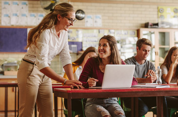Teacher talking to a student at a desk