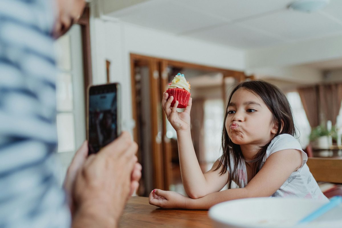 Father Taking a Photo of His Daughter Holding a Cupcake
