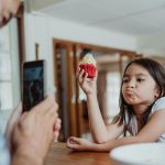 Father Taking a Photo of His Daughter Holding a Cupcake