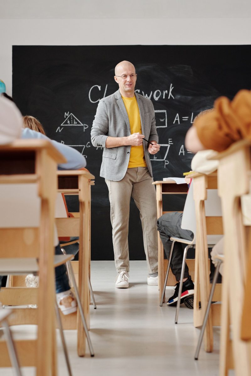 A man standing in front of a blackboard in front of a class of students