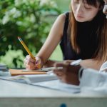 A woman with a pencil in her hand, writing in a notebook